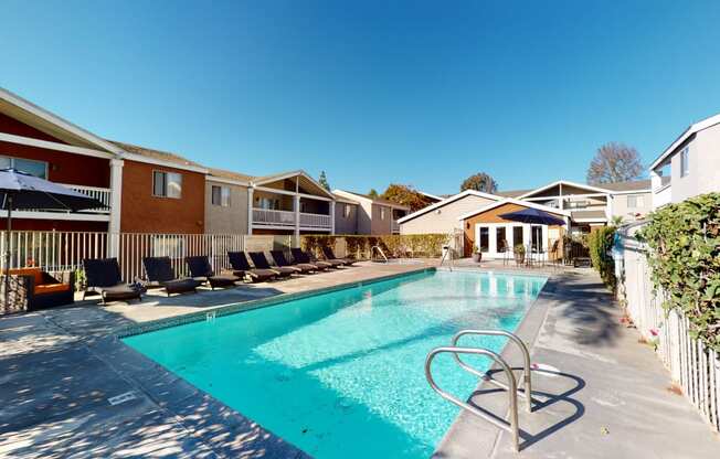 Apartment Ontario CA - Rancho Vista - Outdoor Pool With Clear Water, Lounge Chairs, Additional Seating With Umbrellas, and a Fenced Perimeter