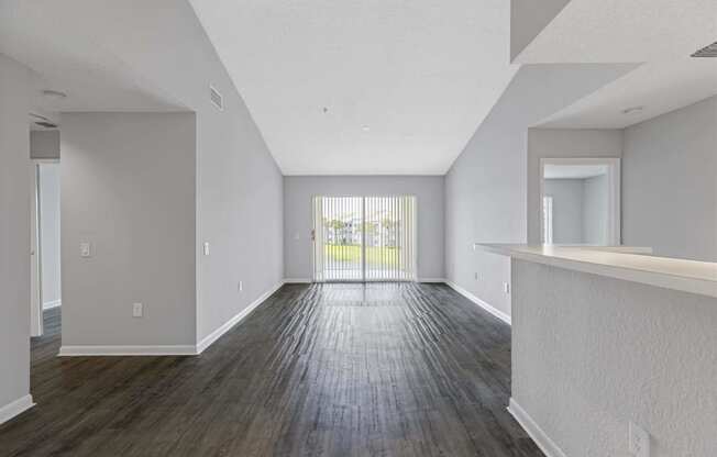 the living room and dining room of an apartment with wood flooring and a balcony