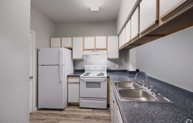 a kitchen with white appliances and a sink and a refrigerator