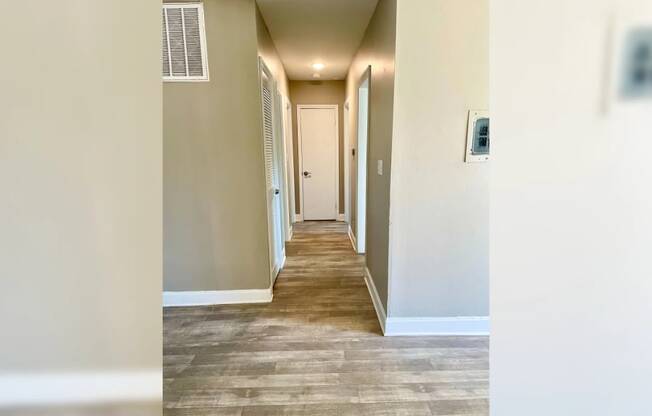 a hallway with a wood floor and white walls and a white door