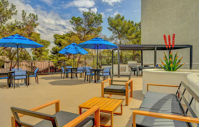 A patio with blue umbrellas and wooden furniture.