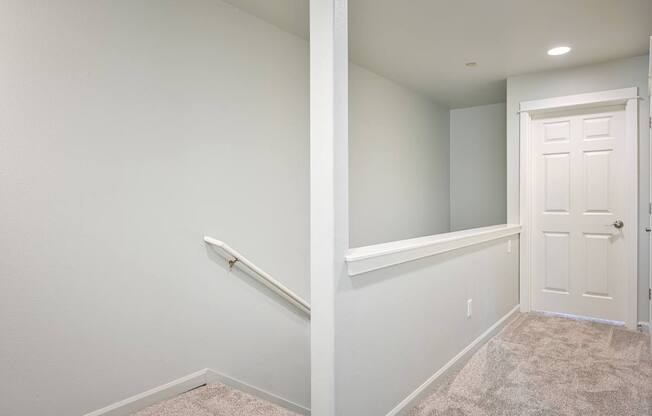 A white door is on the right side of a hallway.