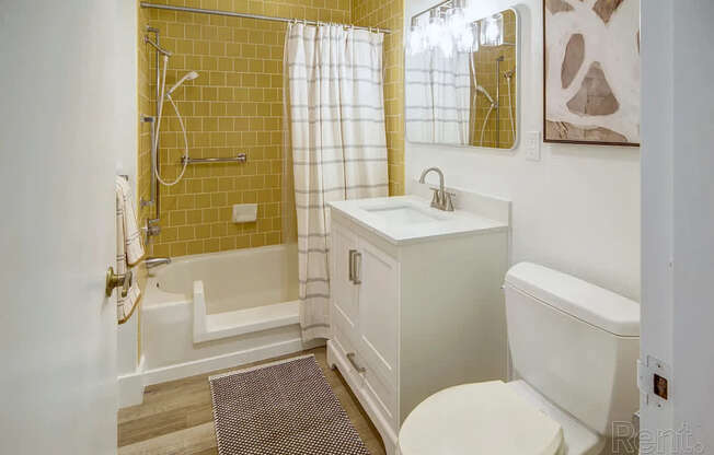 A bathroom with a yellow tiled shower area and a white toilet.