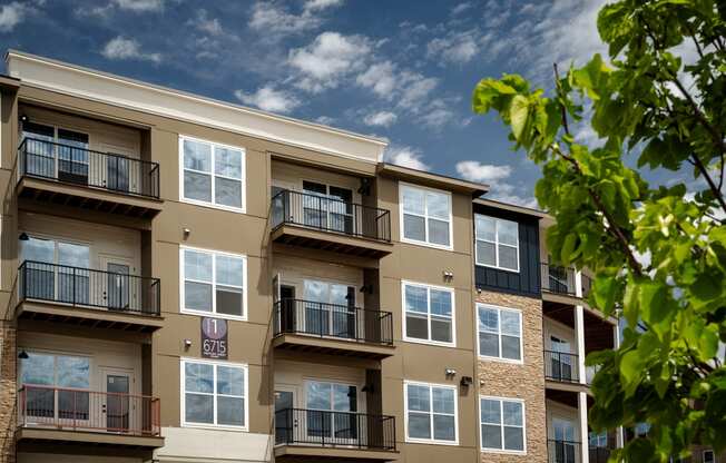 an exterior view of an apartment building with balconies and a tree