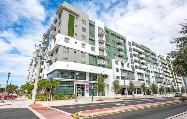 A modern multi-story building with a green vertical garden on the side.