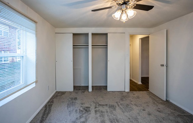 a bedroom with white walls and a ceiling fan