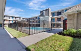 A black fence surrounds a pool in a residential area.