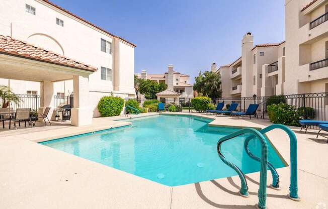 A swimming pool with a diving board in front of apartment buildings.