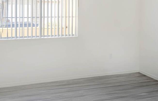 A room with a window and wooden flooring.