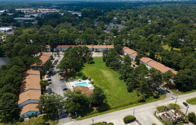 A bird's eye view of a residential area with houses, roads, and a swimming pool.