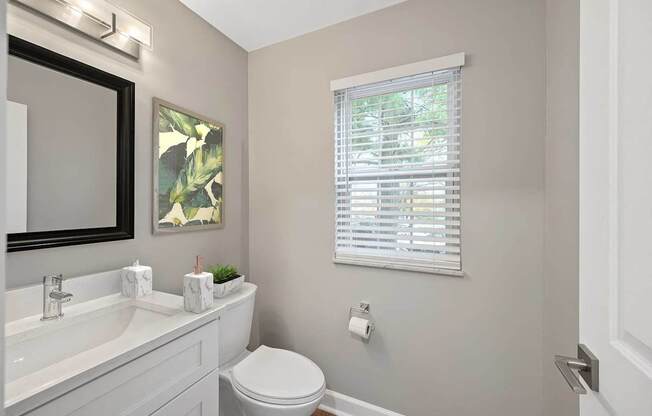 a bathroom with a toilet and a sink and a window