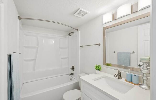 A white bathroom with a toilet, sink, and bathtub.