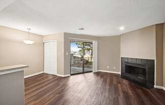 an empty living room with a fireplace and wooden floors