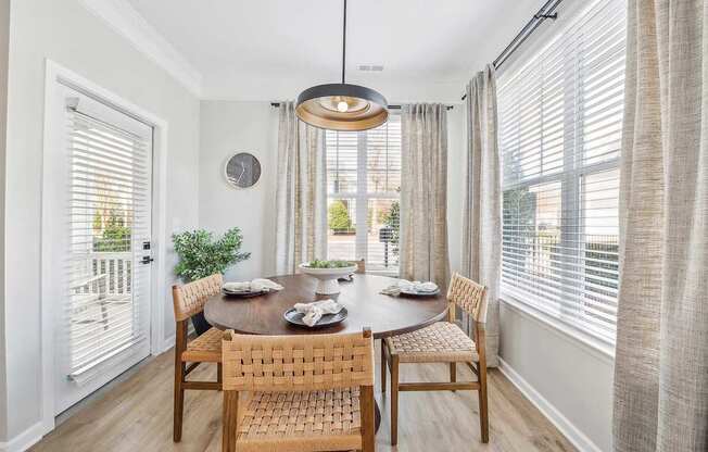 A dining room with a table set for two and a view of the backyard.