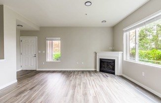 an empty living room with a fireplace and two windows