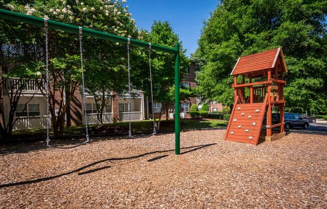 a playground with a swing set and a tree house