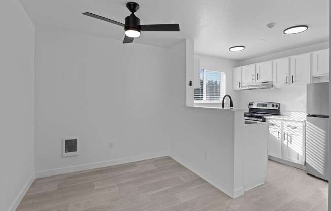 an empty kitchen and living room with a ceiling fan