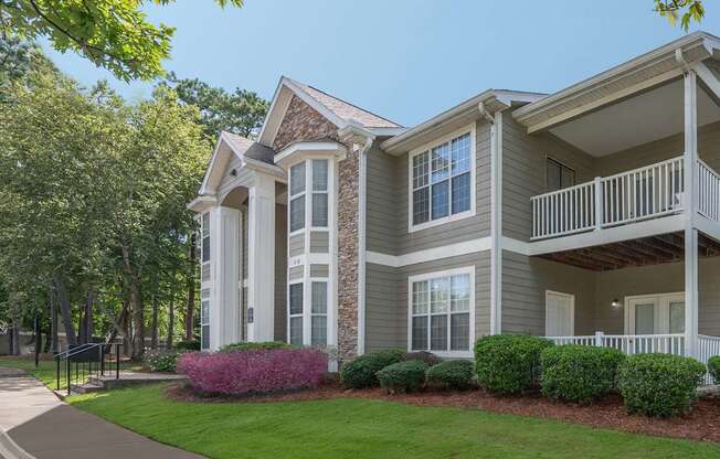 A large two-story house with a balcony and a small garden in front.