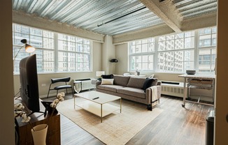 a living room with a couch and a coffee table and large windows