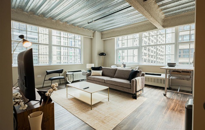 a living room with a couch and a coffee table and large windows