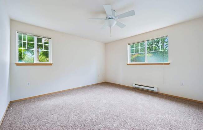Spacious York bedroom with a carpeted floor, a ceiling fan, and two windows at Abbey Rowe Apartments in Olympia, WA
