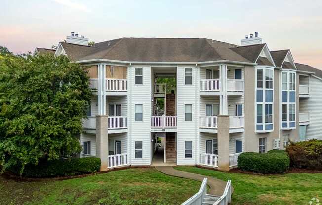 A large white apartment building with a balcony and a staircase leading to the entrance.