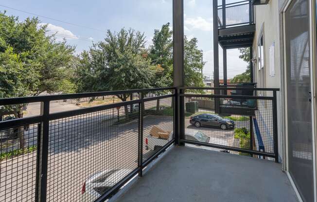 a balcony with a black railing and a car parked in a parking lot