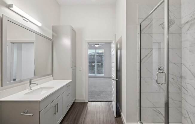 A bathroom with a marble shower and a large mirror.