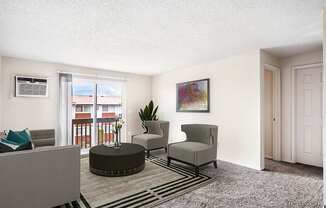 Living room with white walls, taupe carpet, and sliding glass doors to a private balcony. Staged with a gray couch, 2 chairs, a coffee table, and rug.at Wildflower, Kennewick Washington
