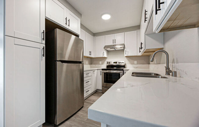 a large kitchen with white cabinets and stainless steel appliances at Citra Apartments LLC, California, 92107