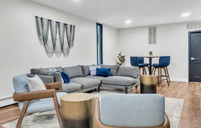 A modern living room with a grey sofa, blue chairs, and a wooden coffee table.