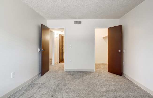 A room with a carpeted floor and two doors.