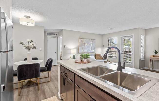 A kitchen with a sink, refrigerator, and a dining table with chairs.