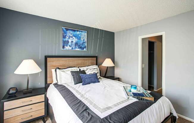 A bedroom with a bed, nightstand, and lamp.