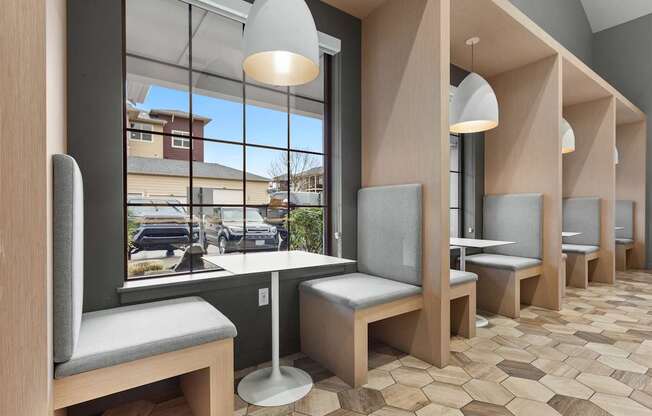 A row of wooden benches with grey cushions are lined up in a room.