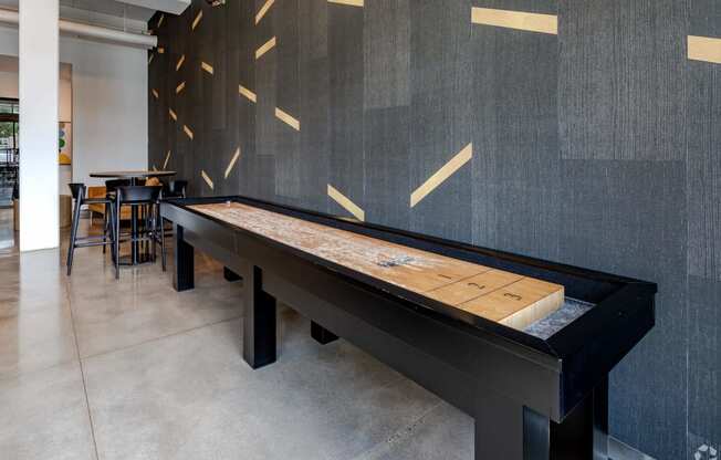 a shuffleboard table in a room with tables and chairs