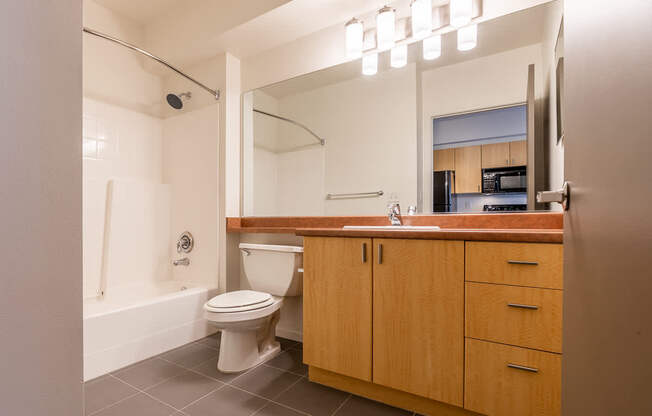 A bathroom with a toilet, sink, and mirror.