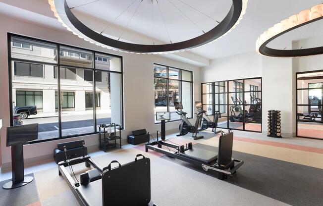 A light-filled fitness studio featuring reformers, bikes, and strength equipment in a flexible layout designed to support a variety of workouts and training styles.