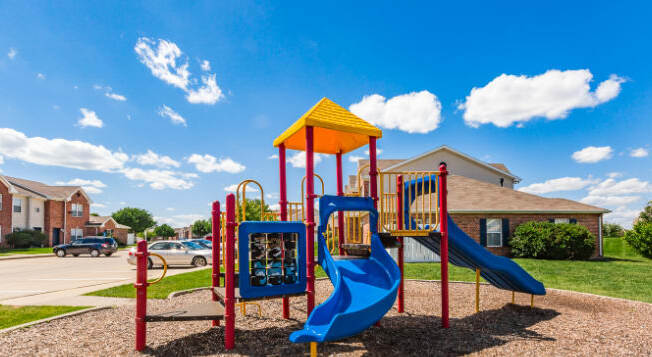 A playground with a blue slide and a yellow canopy.