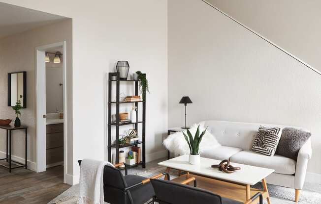 a living room with a white couch and two black chairs