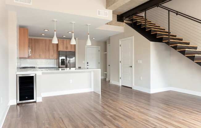 an empty living room with a kitchen and a staircase