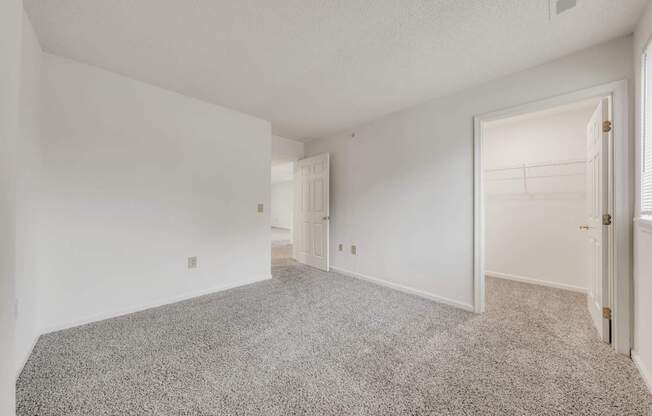 A sparsely furnished room with a carpeted floor and white walls.
