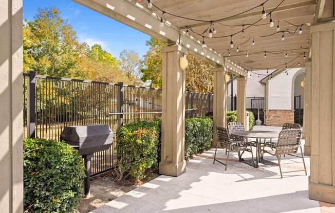 a patio with a table and chairs and a grill