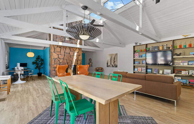 A room with a table and chairs in the foreground and a shelving unit in the background.