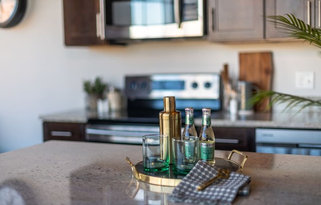 a kitchen island with a tray of wine bottles and a napkin on it at The 22 Apartments, St. Louis, MO 63103