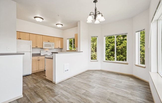A kitchen and dining area with wooden floors and ceiling lights at The Madison Apartments in Olympia, WA