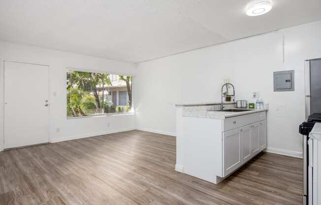 an empty kitchen and living room with white walls and wood floors