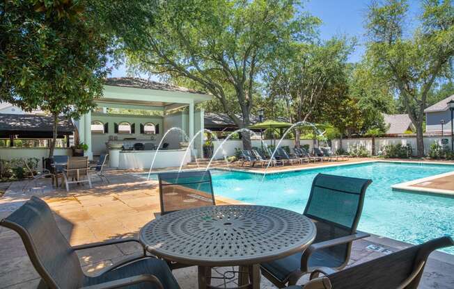 a swimming pool with a patio with a table and chairs