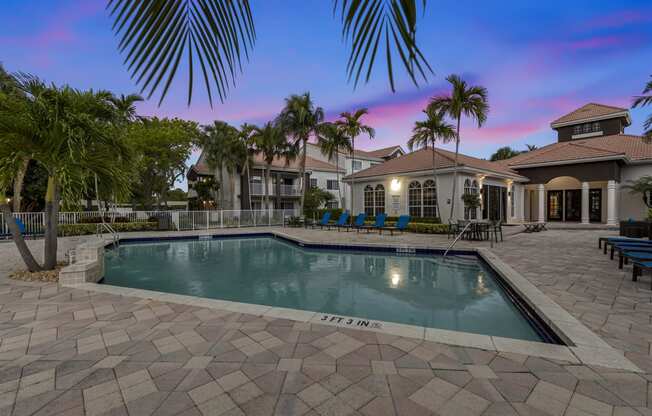 a large swimming pool in front of a house with palm trees