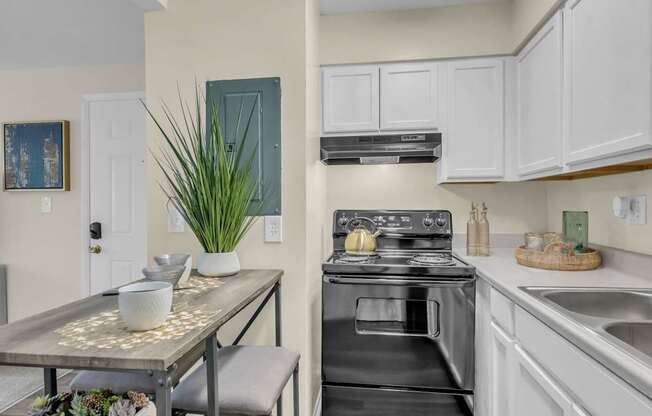 A kitchen with a black oven and white cabinets.